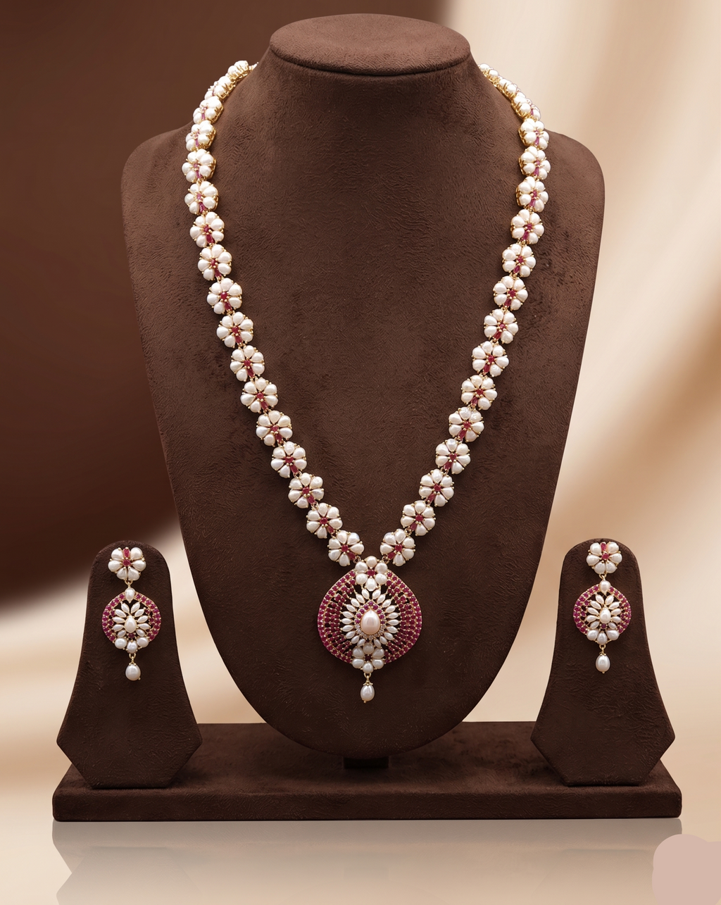 Freshwater pearl long haram set with floral pearl clusters, red stone accents, circular centerpiece, and matching earrings.