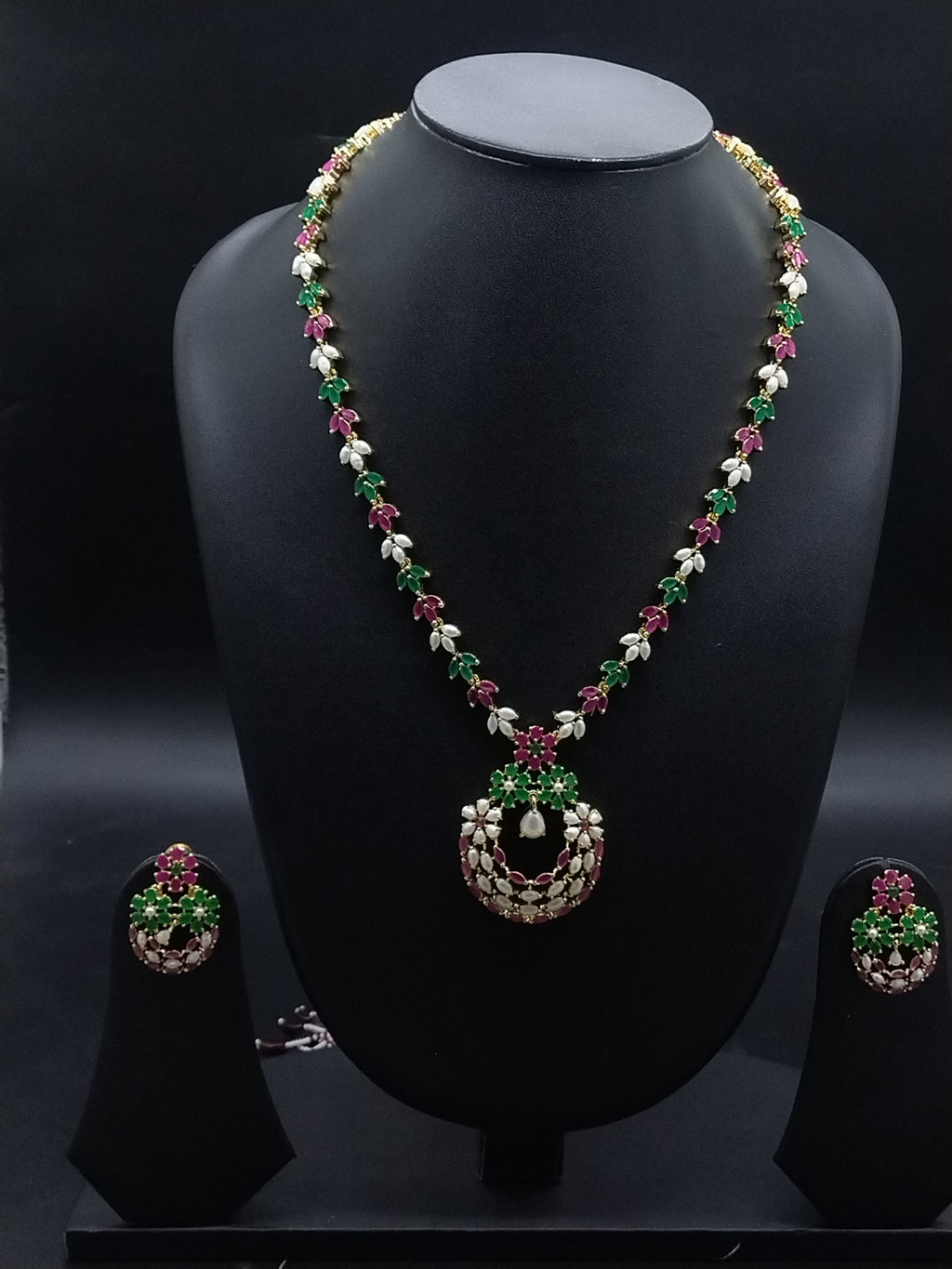 Freshwater pearl long haram set with green and pink stone floral motifs, circular centerpiece, and matching earrings.