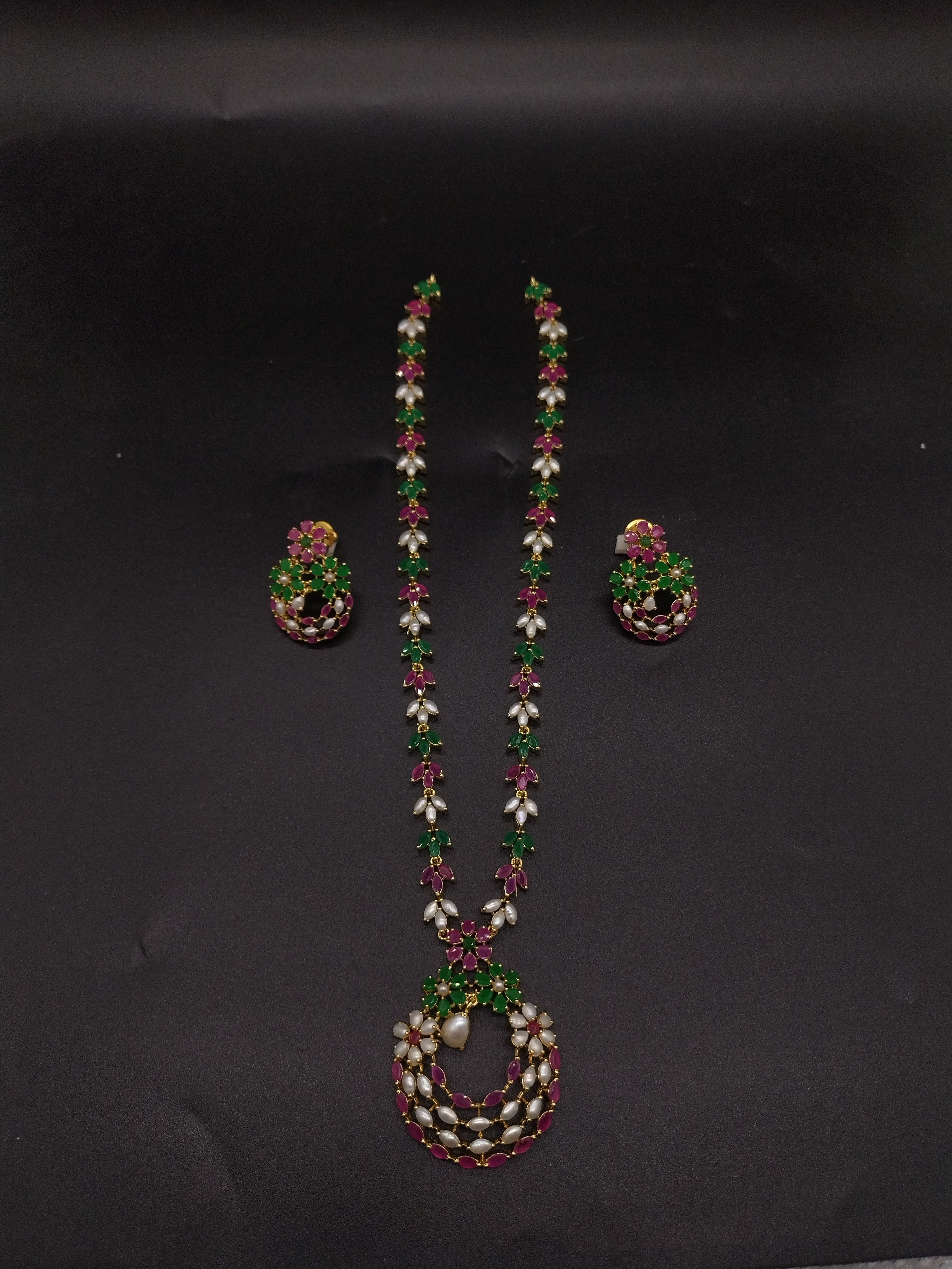 Freshwater pearl long haram set with green and pink stone floral motifs, circular centerpiece, and matching earrings.