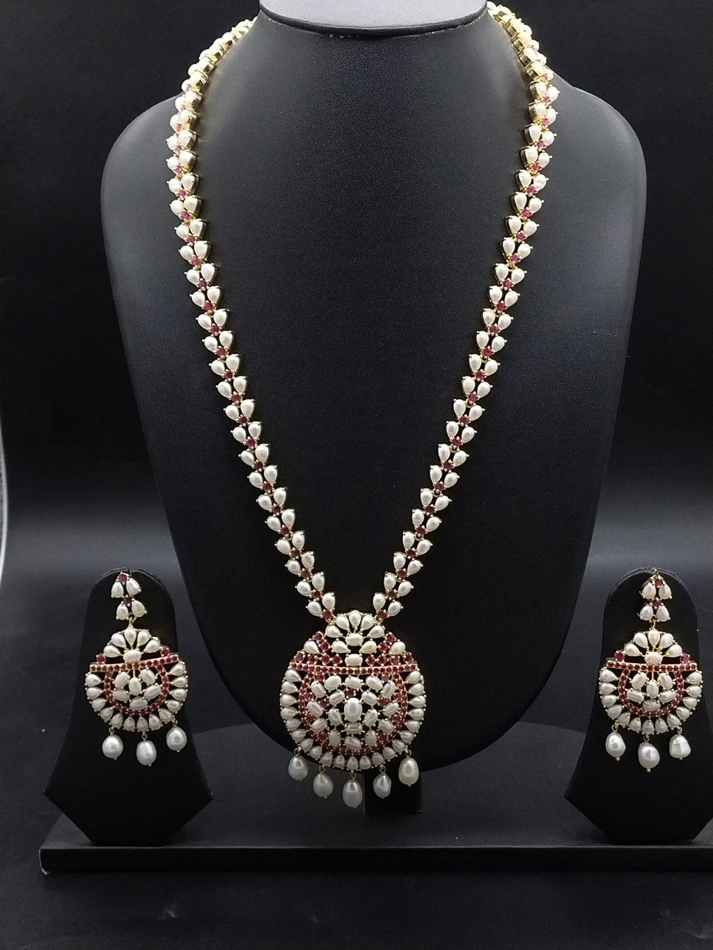 Freshwater pearl long haram set with red and white stone floral motifs, circular pendant with pearl drops, and matching earrings.