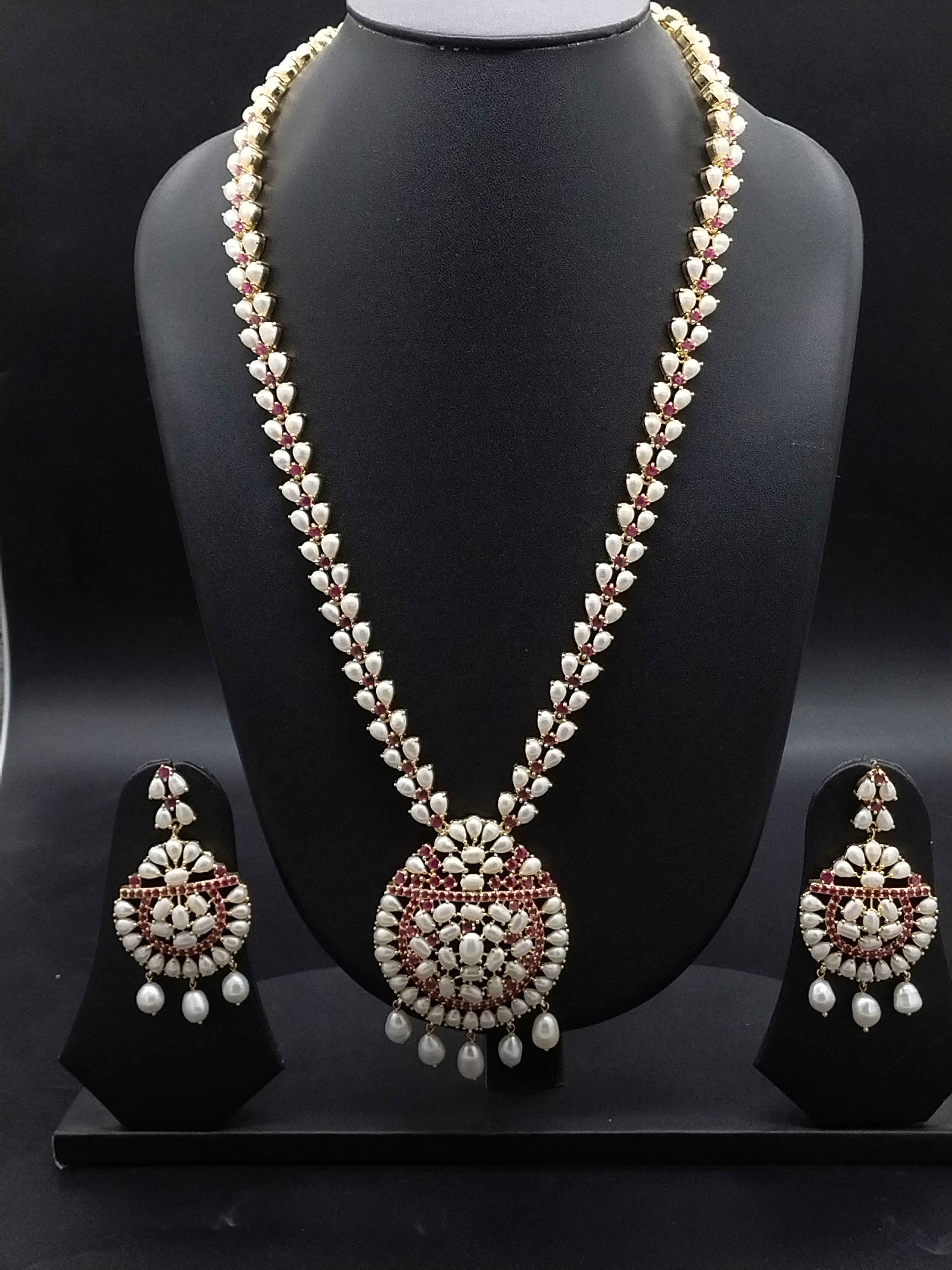 Freshwater pearl long haram set with red and white stone floral motifs, circular pendant with pearl drops, and matching earrings.