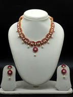 Freshwater pearl necklace set with red stone floral centerpiece, pearl drop detailing, and matching earrings.