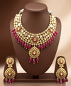 Kundan choker set with white stone detailing, red bead accents, and matching statement earrings.