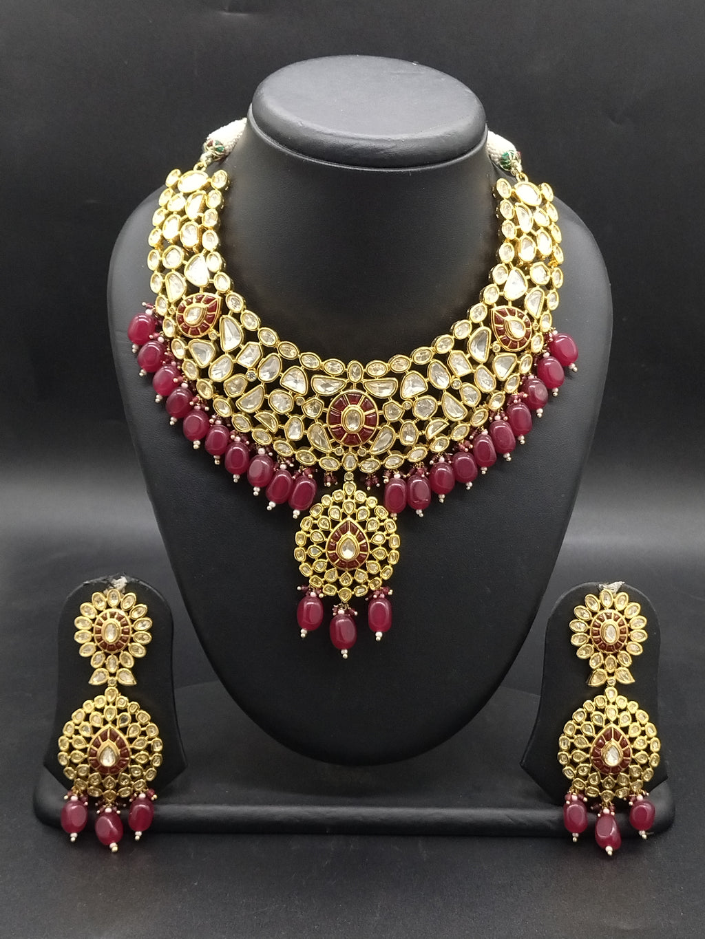 Kundan choker set with white stone detailing, red bead accents, and matching statement earrings.