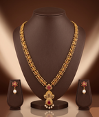 Long haram set with red and white American Diamond stones, ornate floral pendant, pearl drops, and matching earrings.