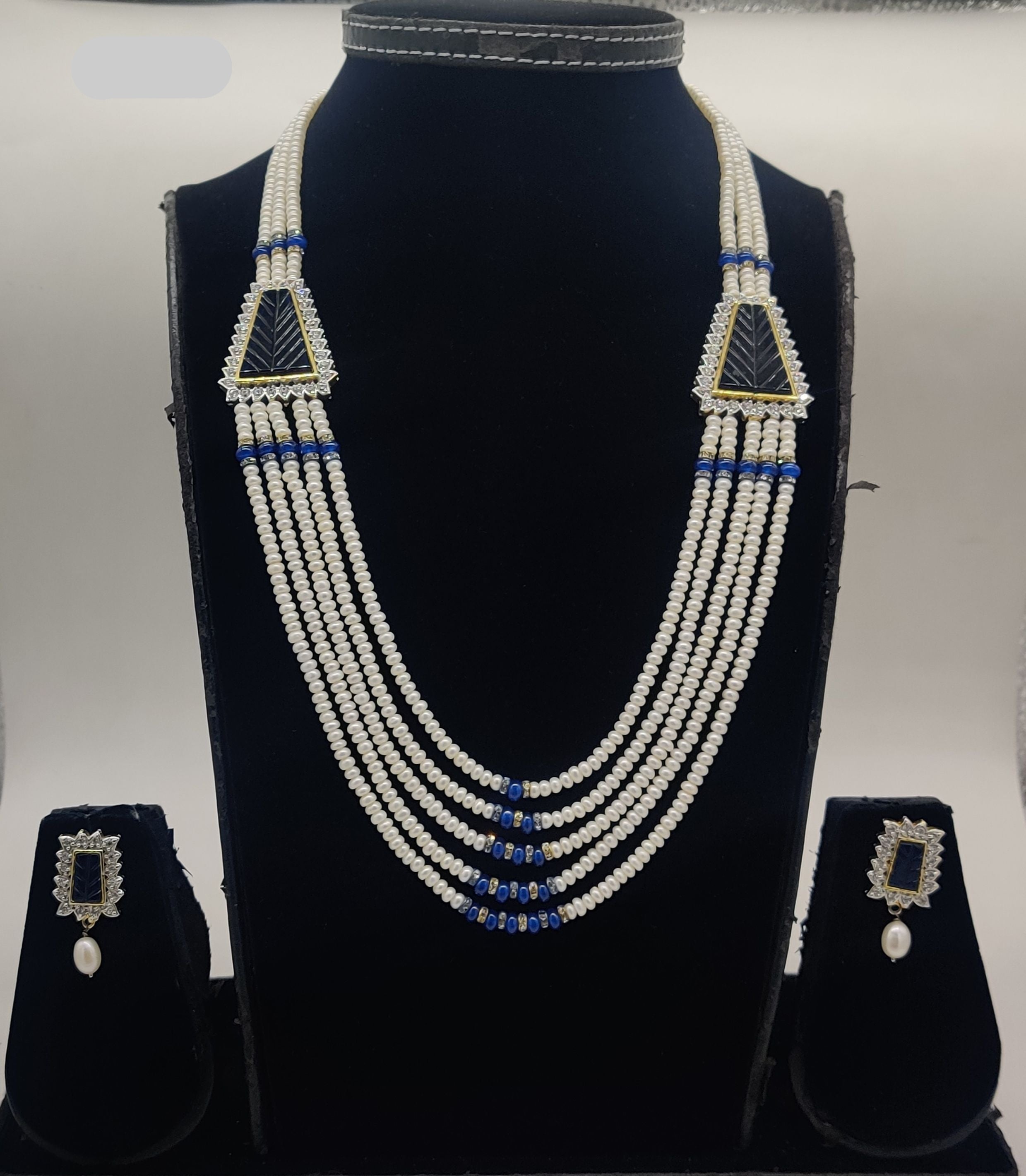 Five-line freshwater pearl broach set with blue bead accents and dual triangular centerpiece elements with matching rectangular earrings.