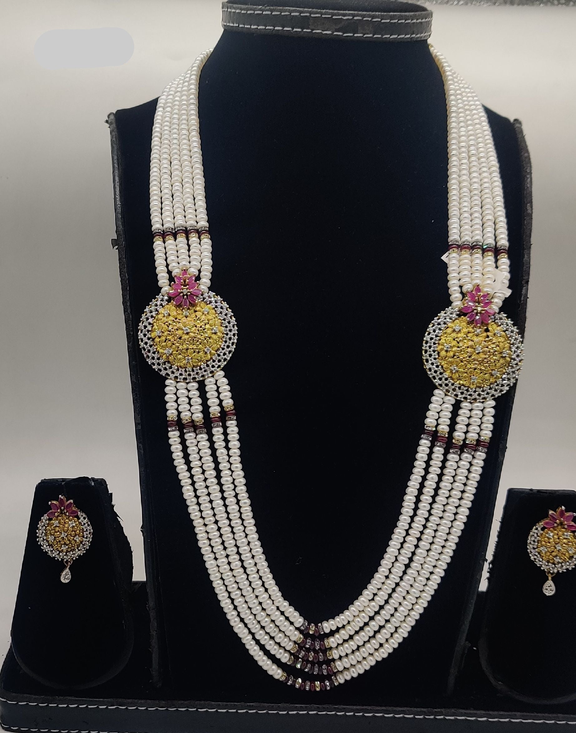 Five-line freshwater pearl broach set with gold temple medallions and pink ruby-tone stones with matching earrings.