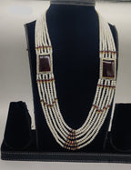 Six-line flat freshwater pearl broach set with dual rectangular red gemstone centerpieces and gold accents.