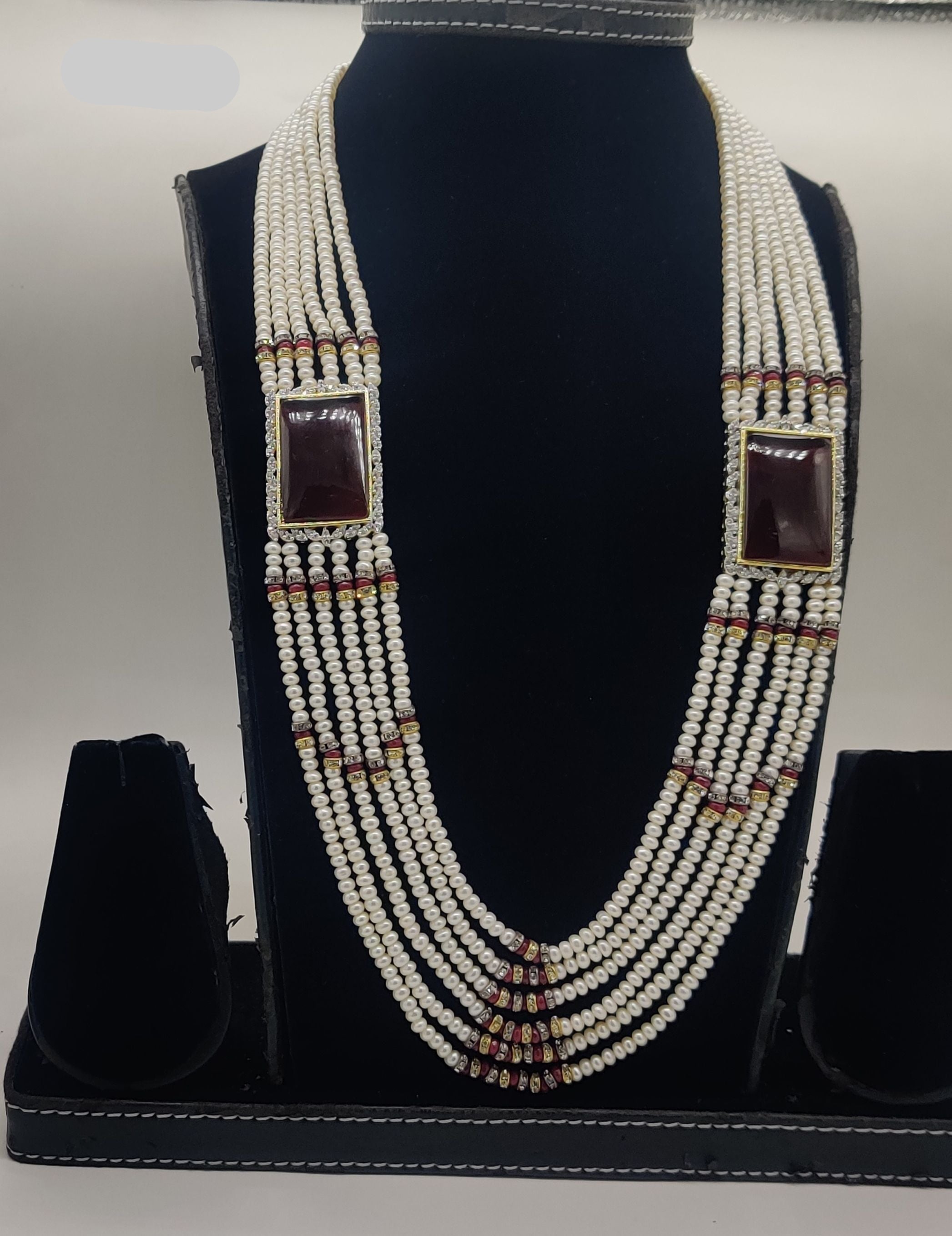Six-line flat freshwater pearl broach set with dual rectangular red gemstone centerpieces and gold accents.