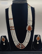 Four-line flat freshwater pearl and coral broach set with teardrop orange stone centerpiece and matching earrings.