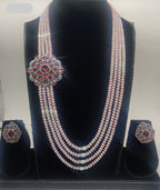 Four-line pink freshwater pearl broach set with floral pink and white stone centerpiece and matching stud earrings.