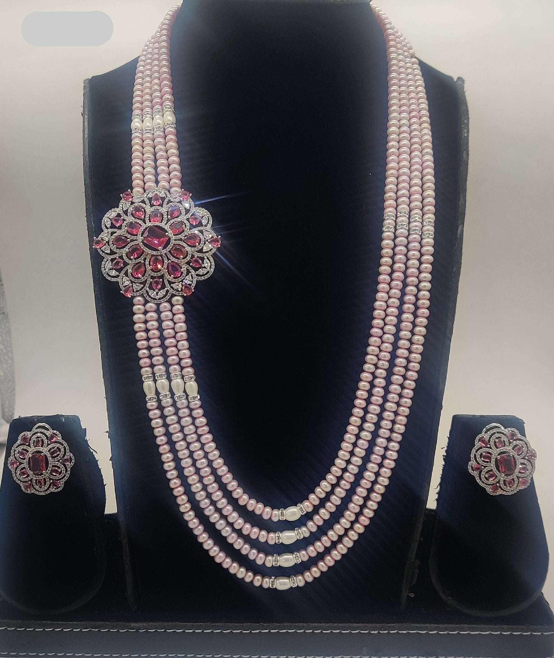 Four-line pink freshwater pearl broach set with floral pink and white stone centerpiece and matching stud earrings.