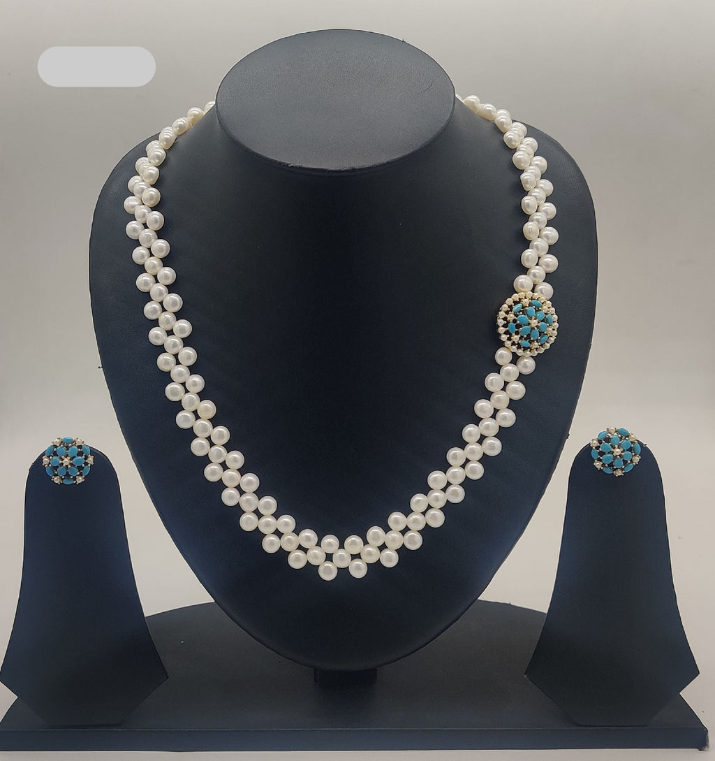 Two-line freshwater pearl zigzag broach set with circular turquoise and gold-toned centerpiece and matching earrings.