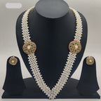 V-shaped freshwater pearl broach set with dual round pearl-centered medallions and red green stone detailing with matching stud earrings.