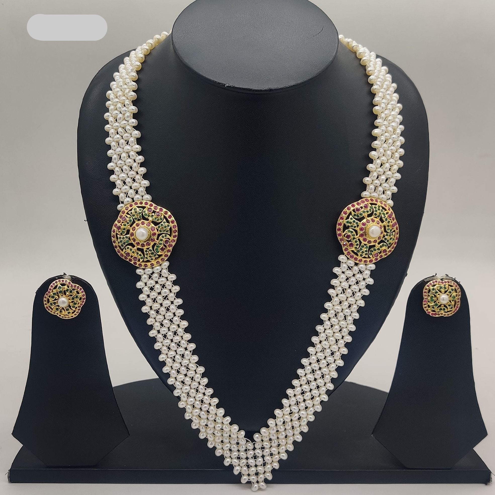 V-shaped freshwater pearl broach set with dual round pearl-centered medallions and red green stone detailing with matching stud earrings.