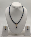 One line freshwater pearl necklace and earrings set with dark beads, gold accents, and black teardrop pendant