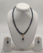 One line freshwater pearl necklace and earrings set with dark beads, gold accents, and black teardrop pendant
