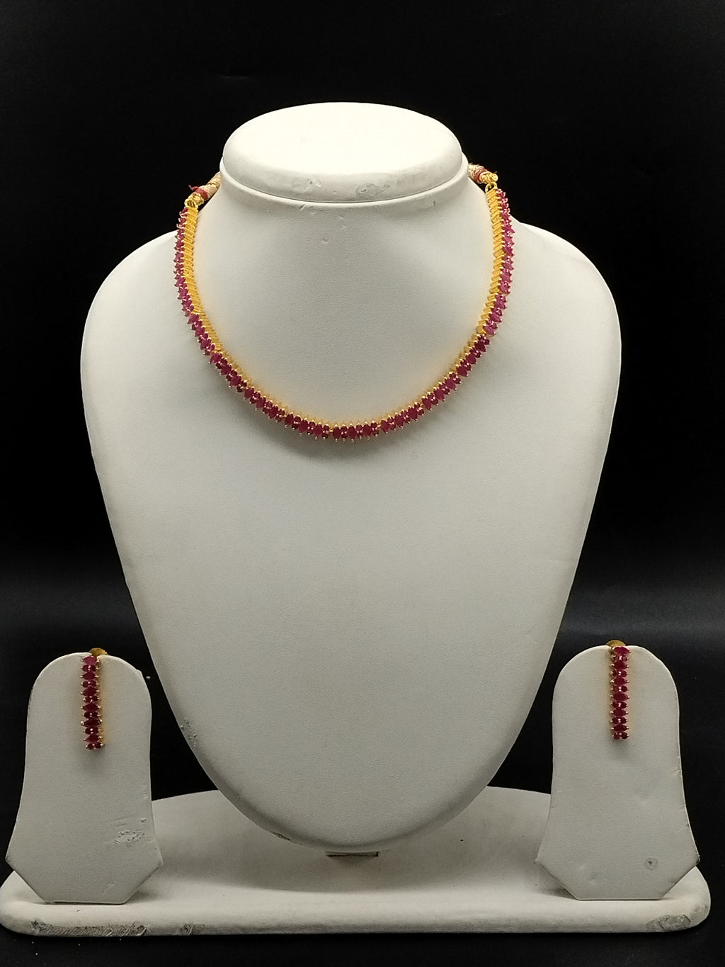 Red stone designer necklace set with oval-cut stones, gold-toned bead accents, and matching long drop earrings.