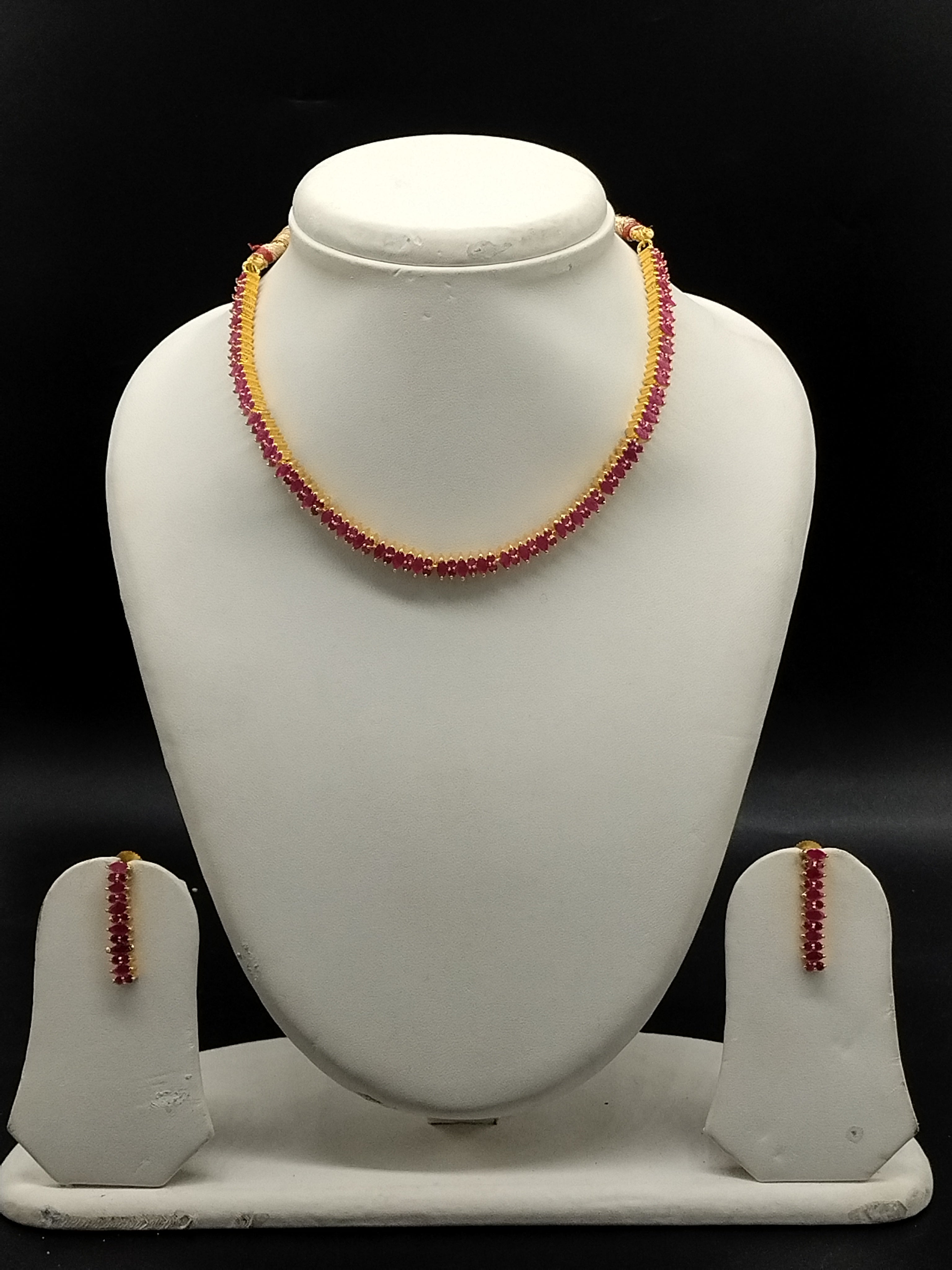 Red stone designer necklace set with oval-cut stones, gold-toned bead accents, and matching long drop earrings.