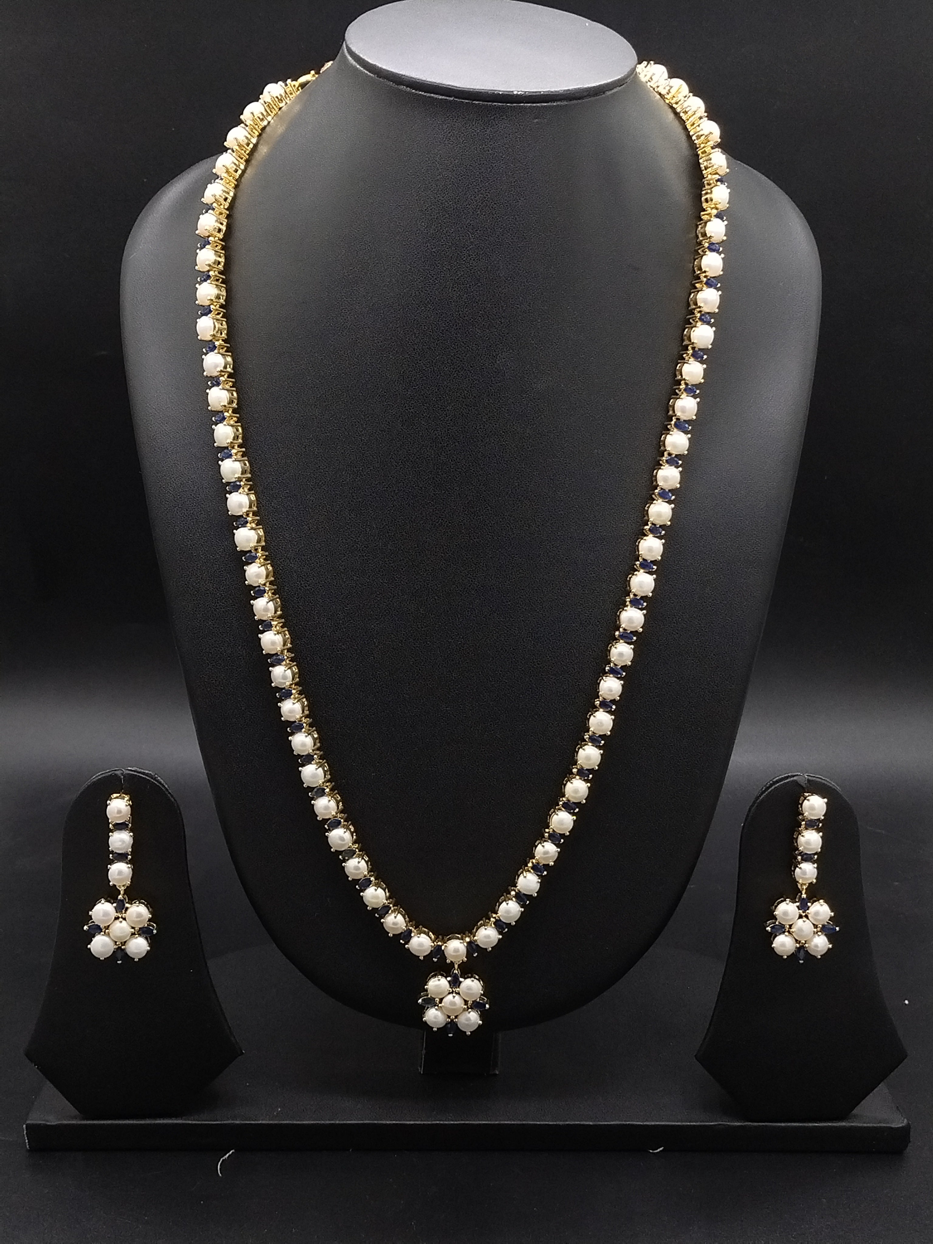 Single-line freshwater pearl long haram set with blue stone floral centerpiece and matching drop earrings.