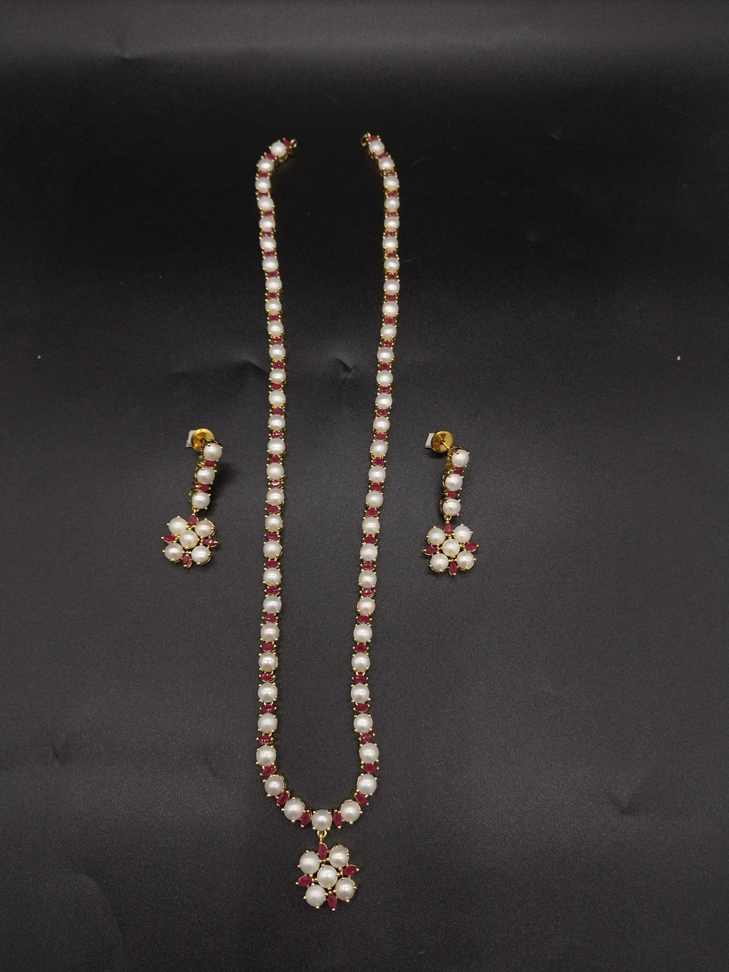 Single-line freshwater pearl long haram set with floral pearl pendant, red American Diamond stone accents, and matching earrings.