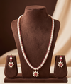 Single-line freshwater pearl long haram set with floral red American Diamond centerpiece and matching drop earrings.