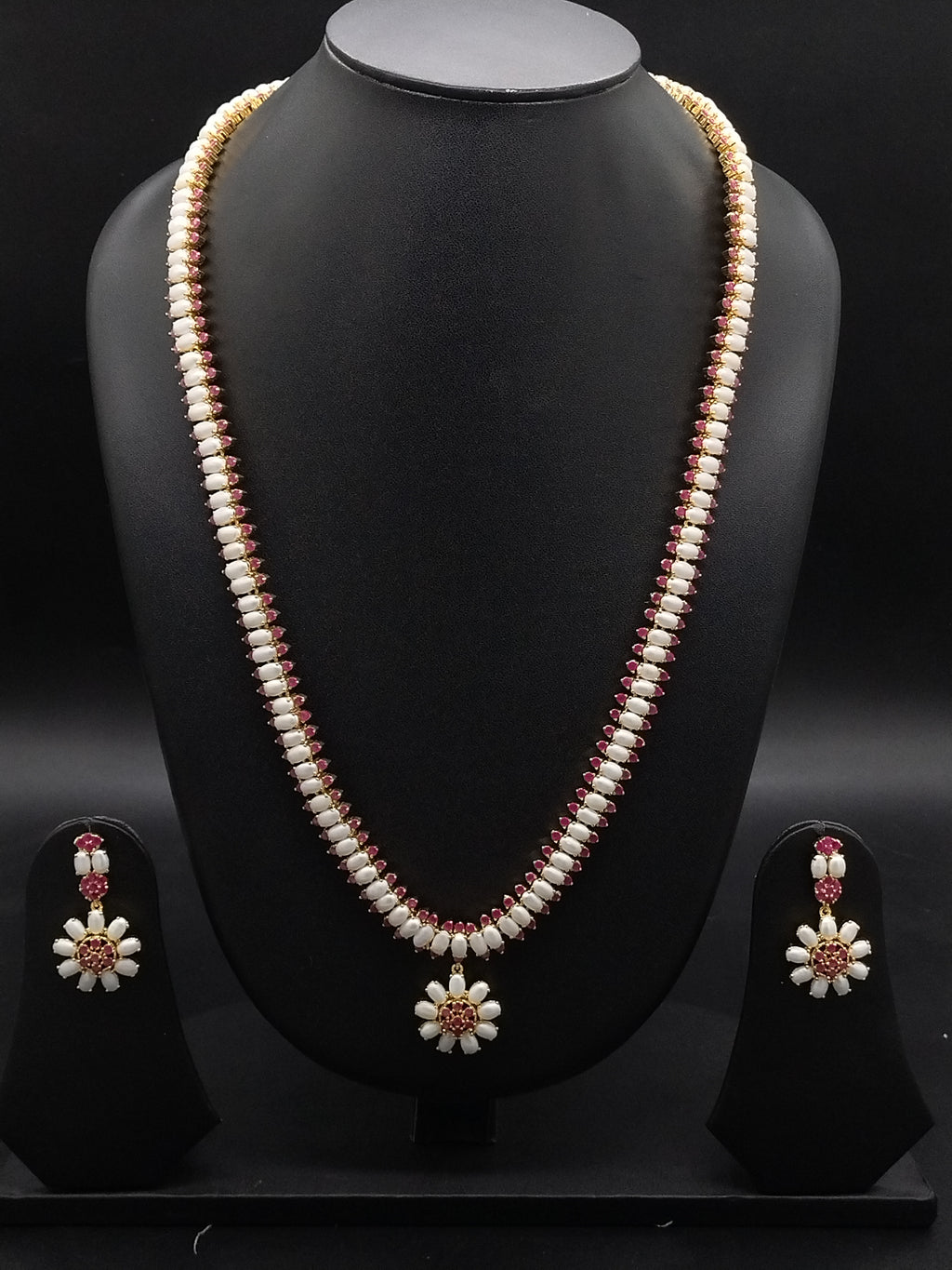 Single-line freshwater pearl long haram set with floral red American Diamond centerpiece and matching drop earrings.