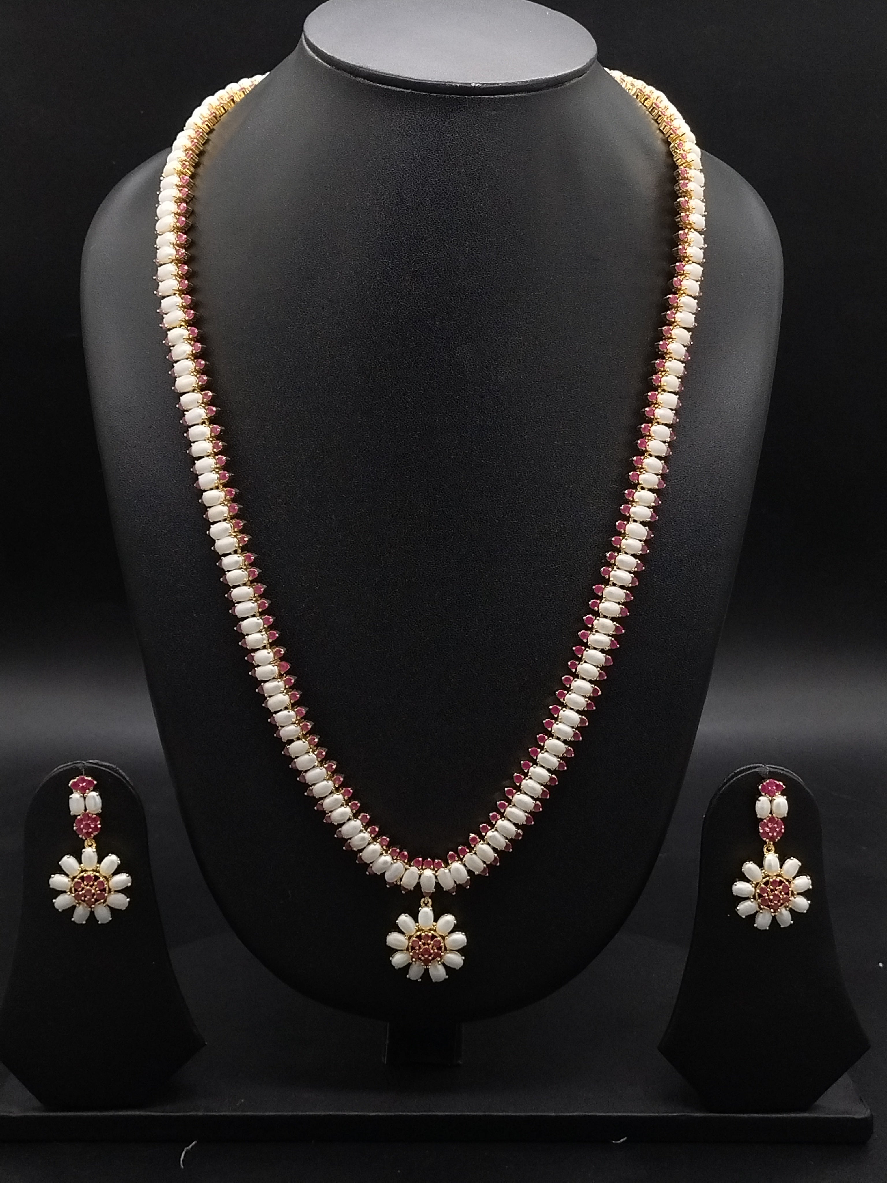 Single-line freshwater pearl long haram set with floral red American Diamond centerpiece and matching drop earrings.