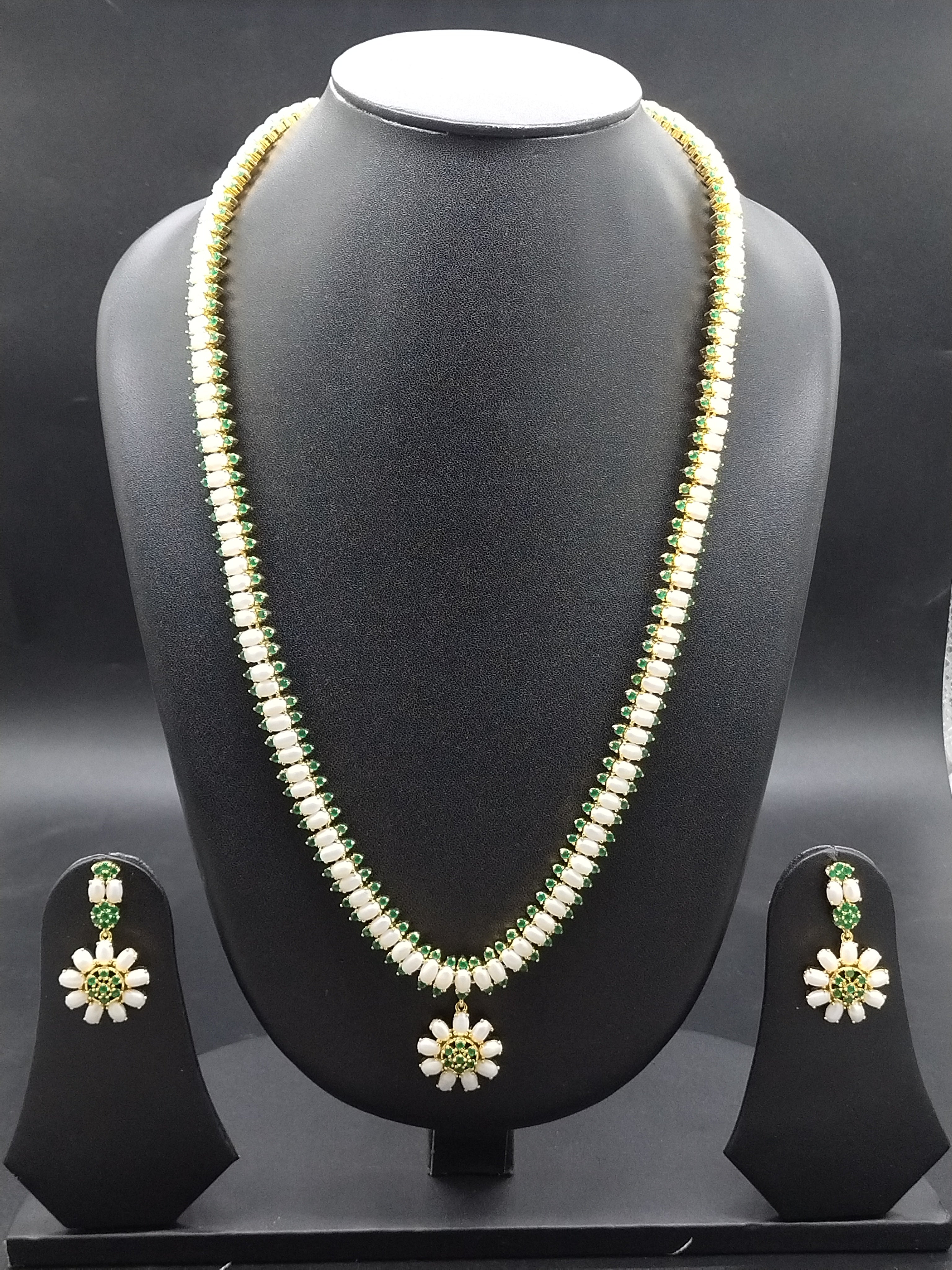 Single-line freshwater pearl long haram set with green stone floral centerpiece and matching drop earrings.