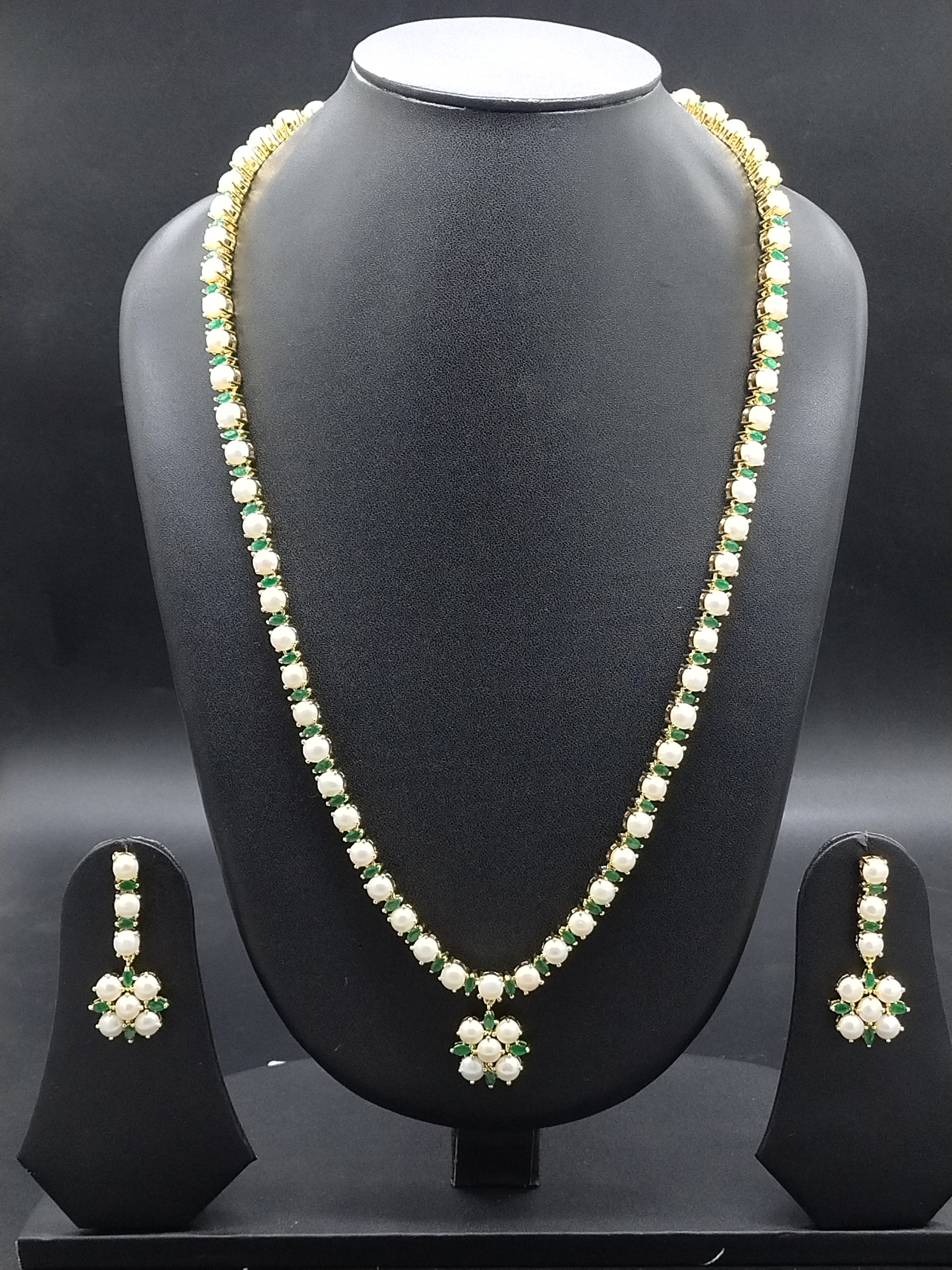Single-line freshwater pearl long haram set with green stone floral pendant and matching drop earrings.