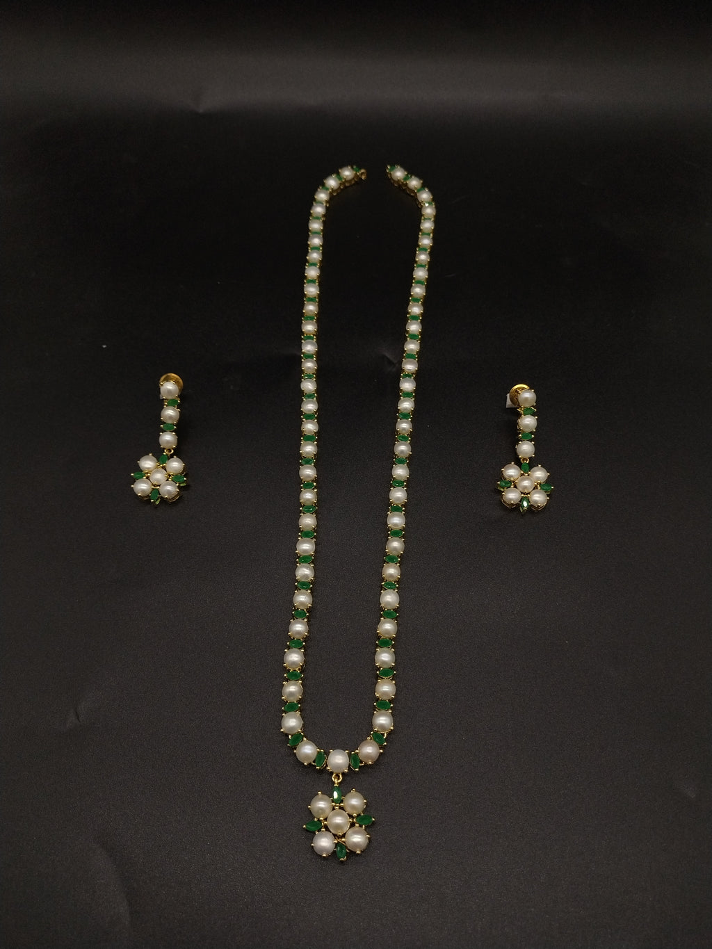 Single-line freshwater pearl long haram set with green stone floral pendant and matching drop earrings.