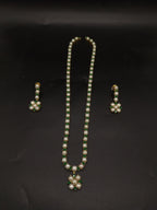 Single-line freshwater pearl long haram set with green stone floral pendant and matching drop earrings.