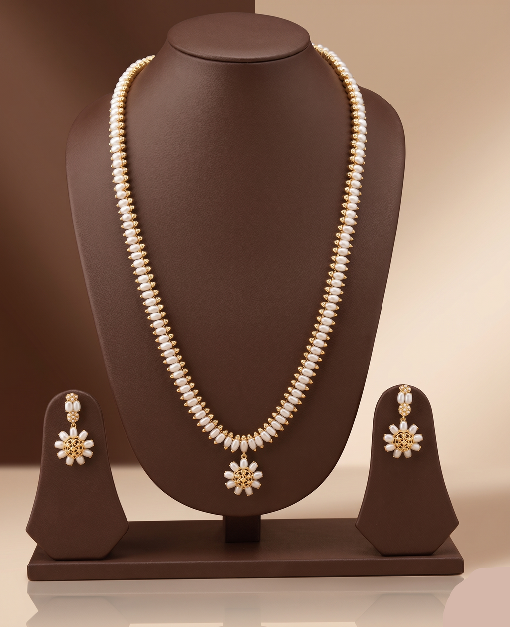 Three-line freshwater pearl long haram set with sunburst floral pendant and matching floral earrings.