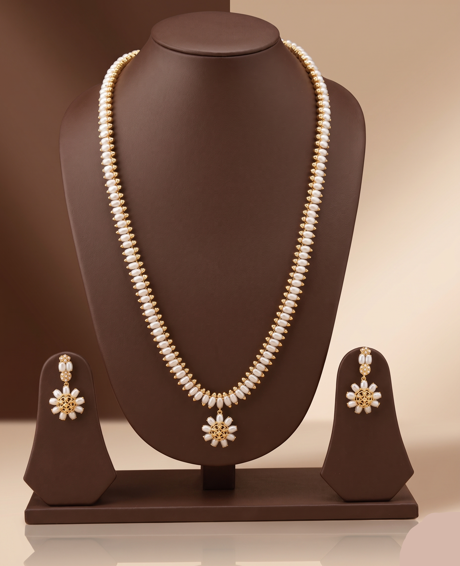 Three-line freshwater pearl long haram set with sunburst floral pendant and matching floral earrings.