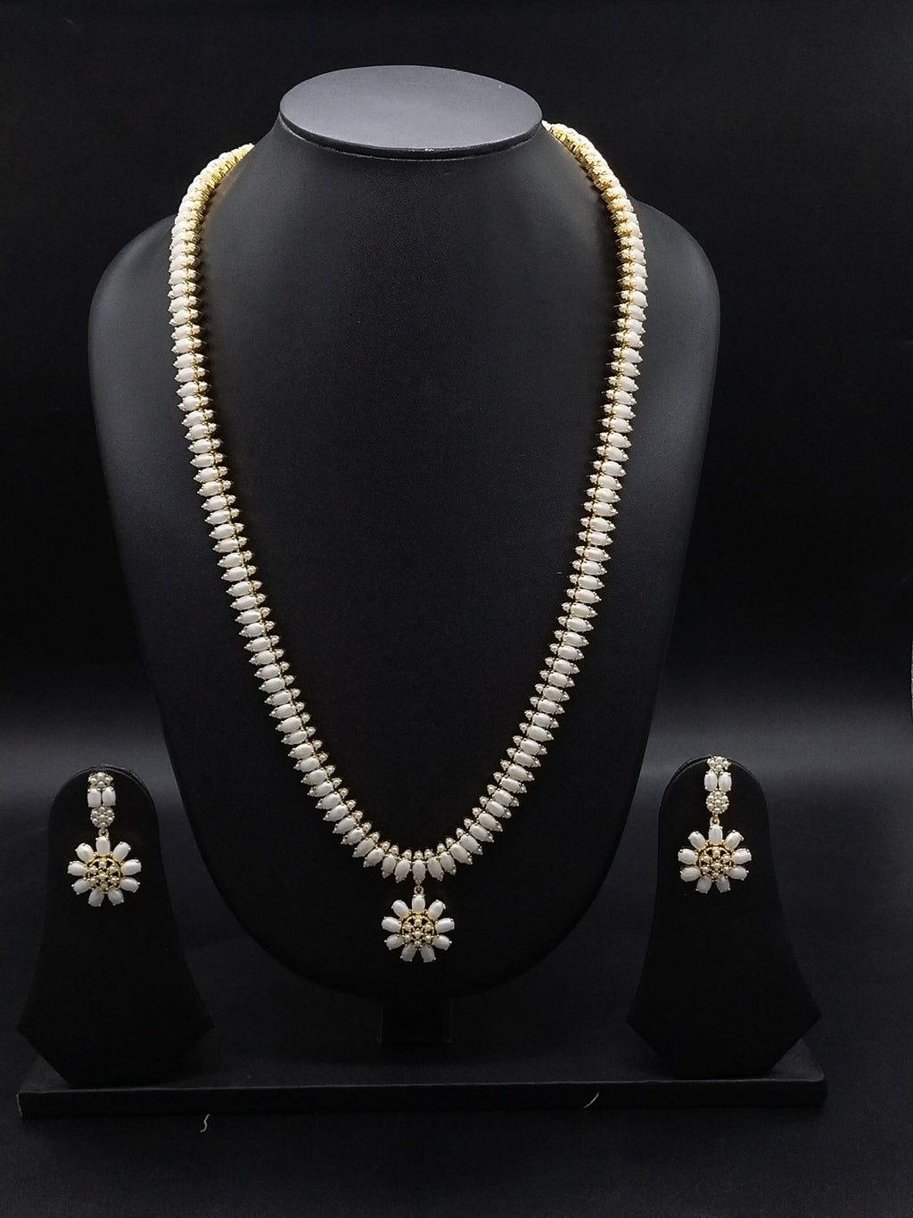 Three-line freshwater pearl long haram set with sunburst floral pendant and matching floral earrings.