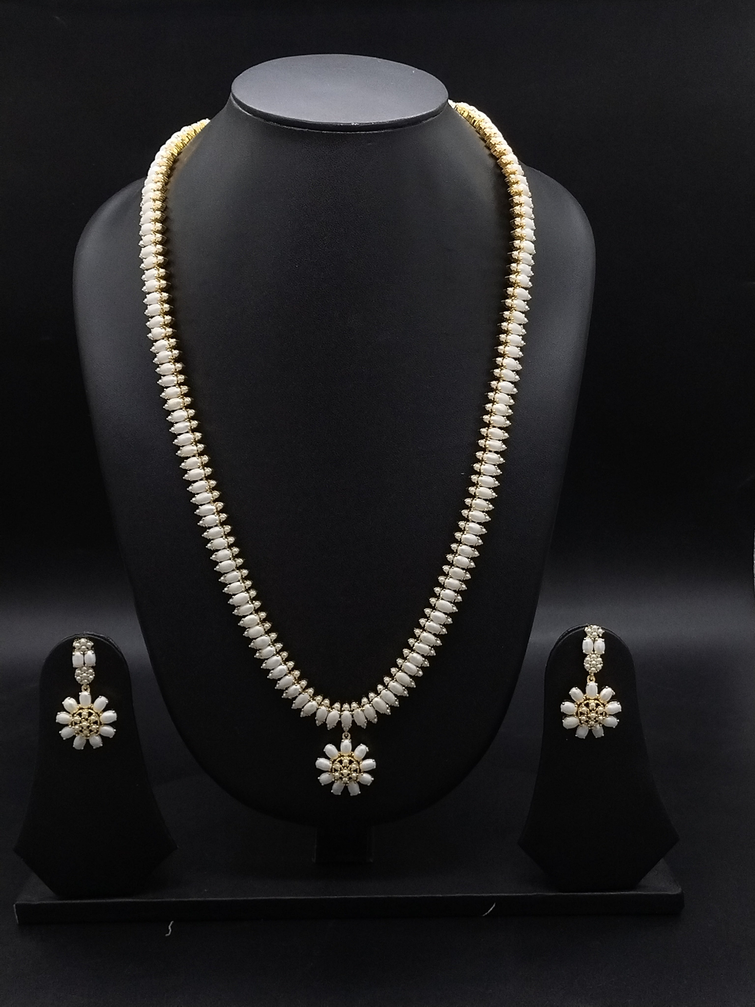 Three-line freshwater pearl long haram set with sunburst floral pendant and matching floral earrings.