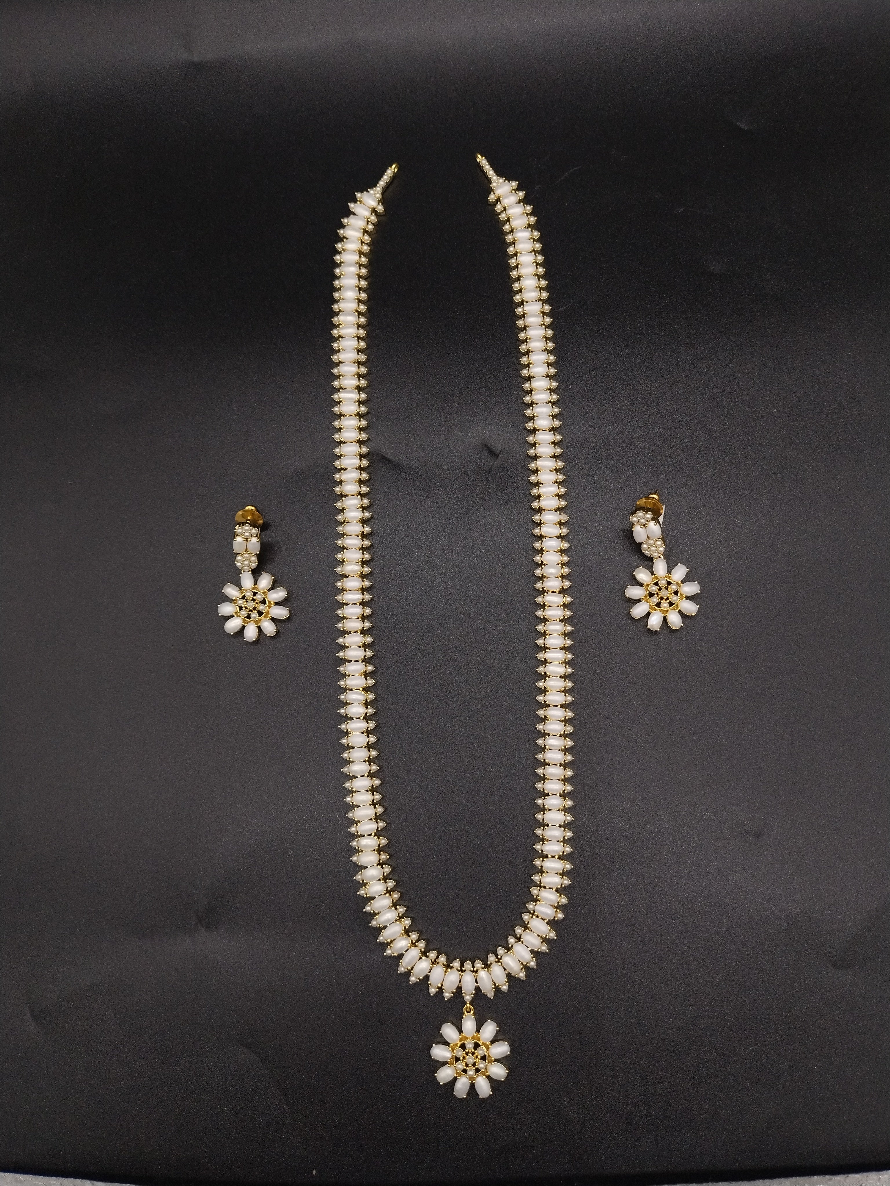 Three-line freshwater pearl long haram set with sunburst floral pendant and matching floral earrings.