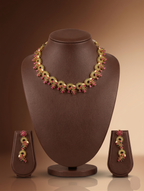 Traditional temple necklace set with red and green stones, floral and mango motifs, and matching drop earrings.