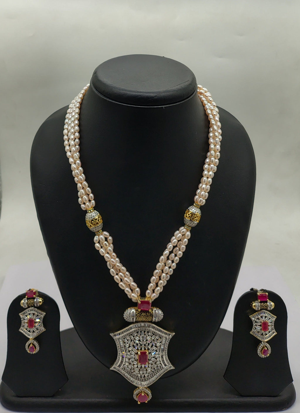 four line freshwater pearl pendant necklace set with peach oval pearls and ornate shield pendant